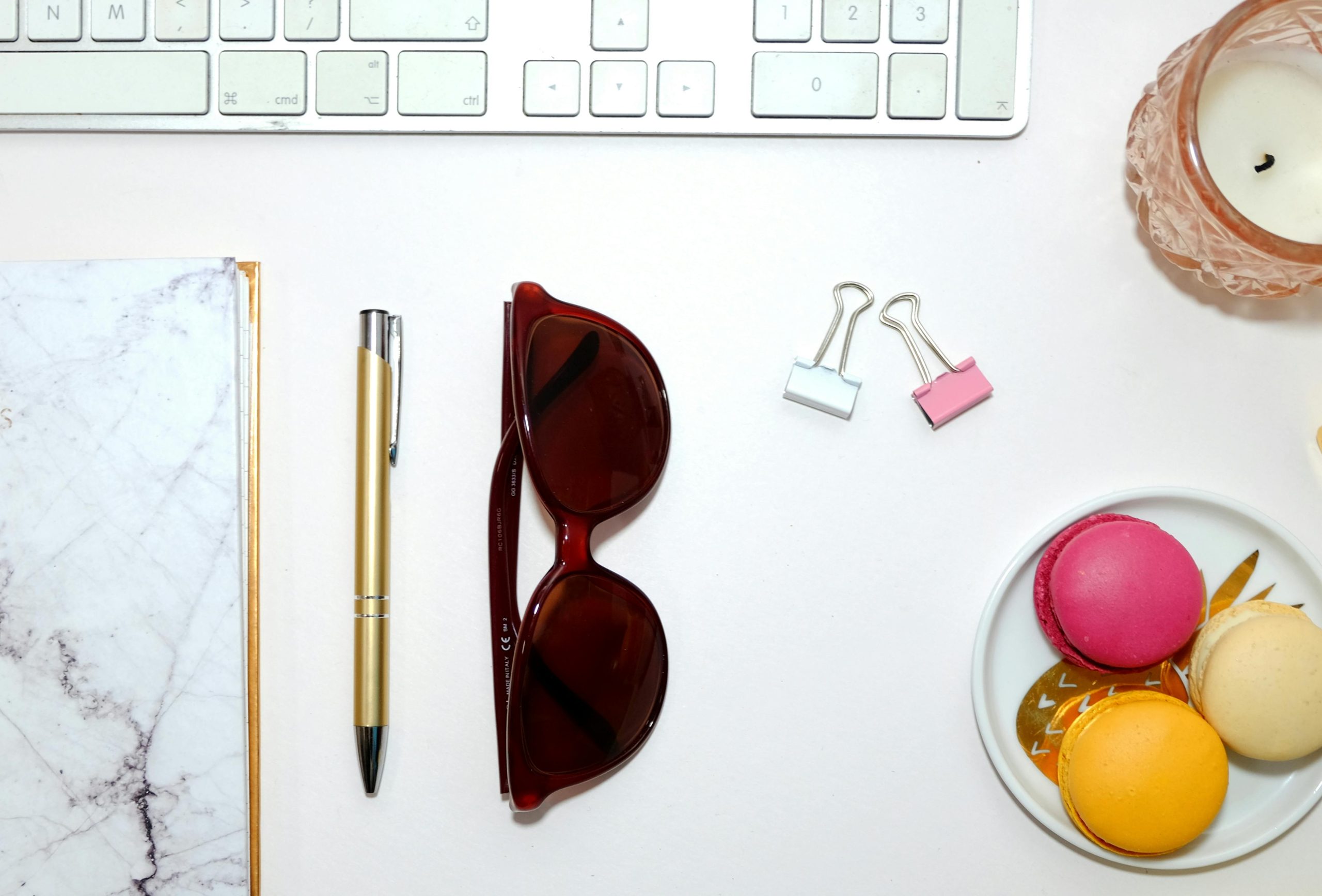 Aesthetic desktop flatlay with sunglasses, colorful macarons, and stationary items