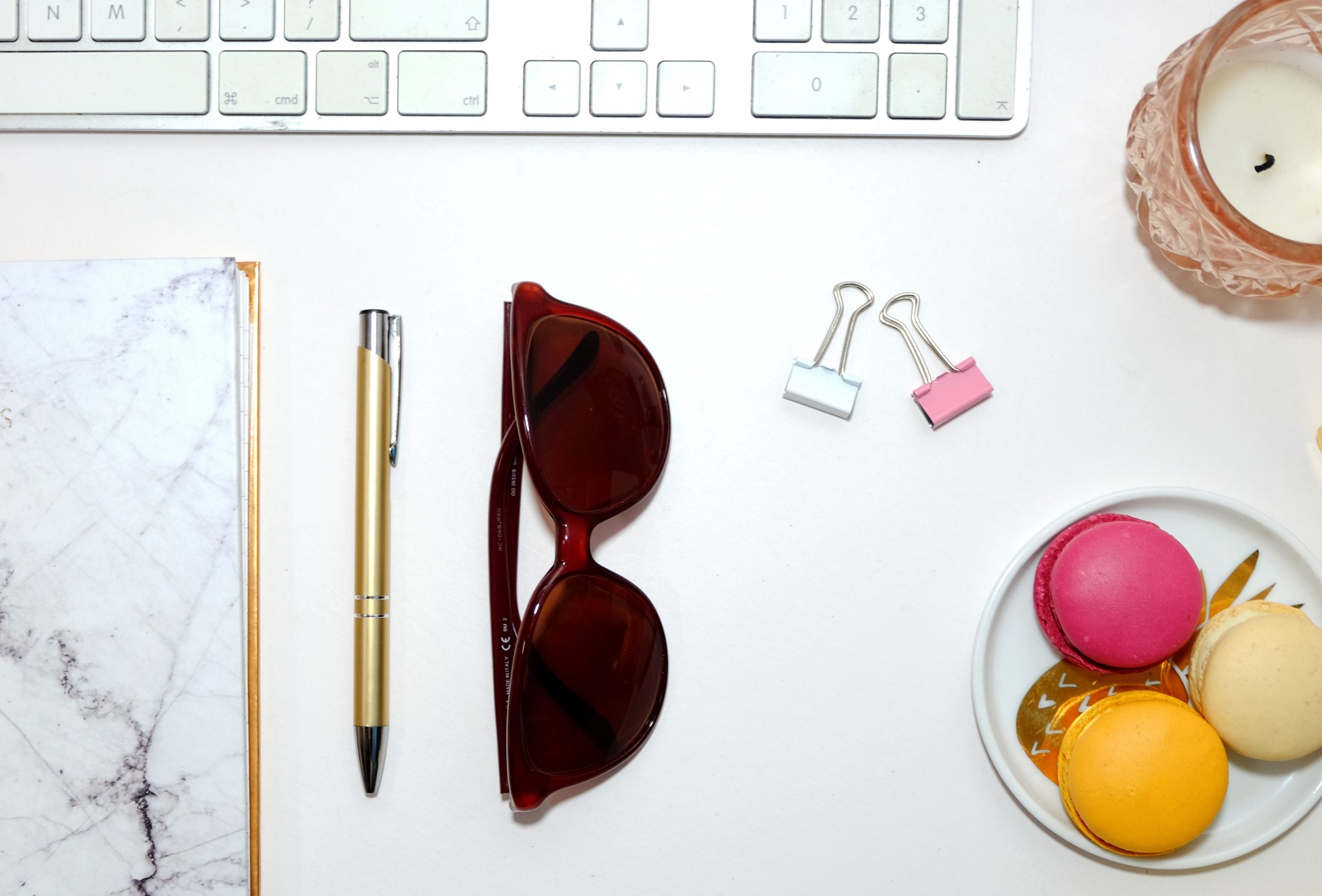 Aesthetic desktop flatlay with sunglasses, colorful macarons, and stationary items